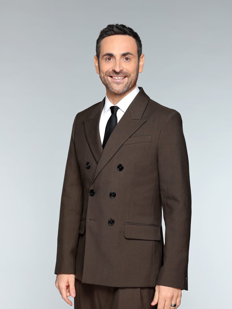 Camille Combal, animateur, en costume marron, portrait studio pour Danse avec les stars